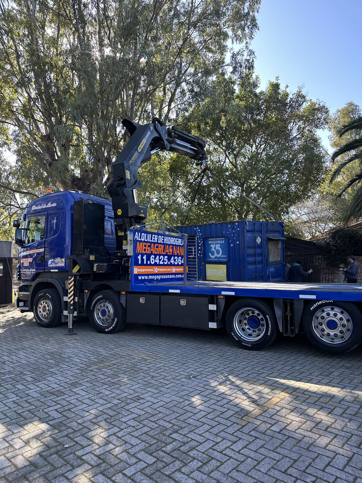 Camión Scania azul con hidrogrúa Palfinger cargando contenedor